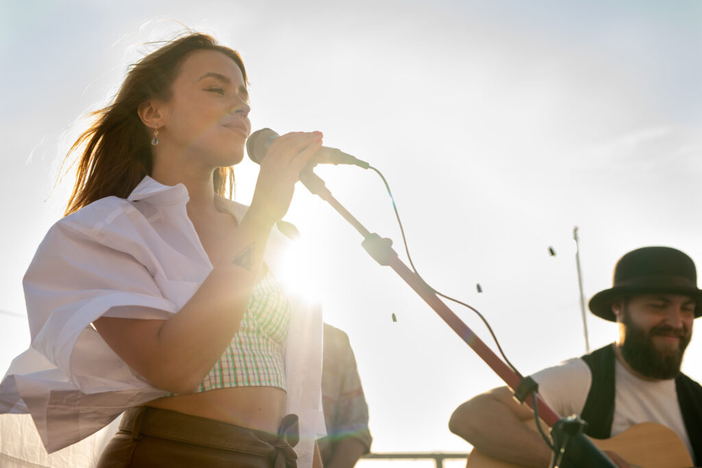 Young female singer with mike standing against bearded man with guitar
